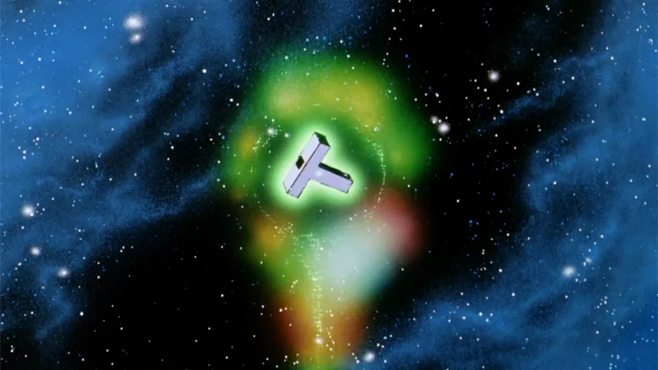 宇宙空間で緑色の光に包まれるT字型の部品